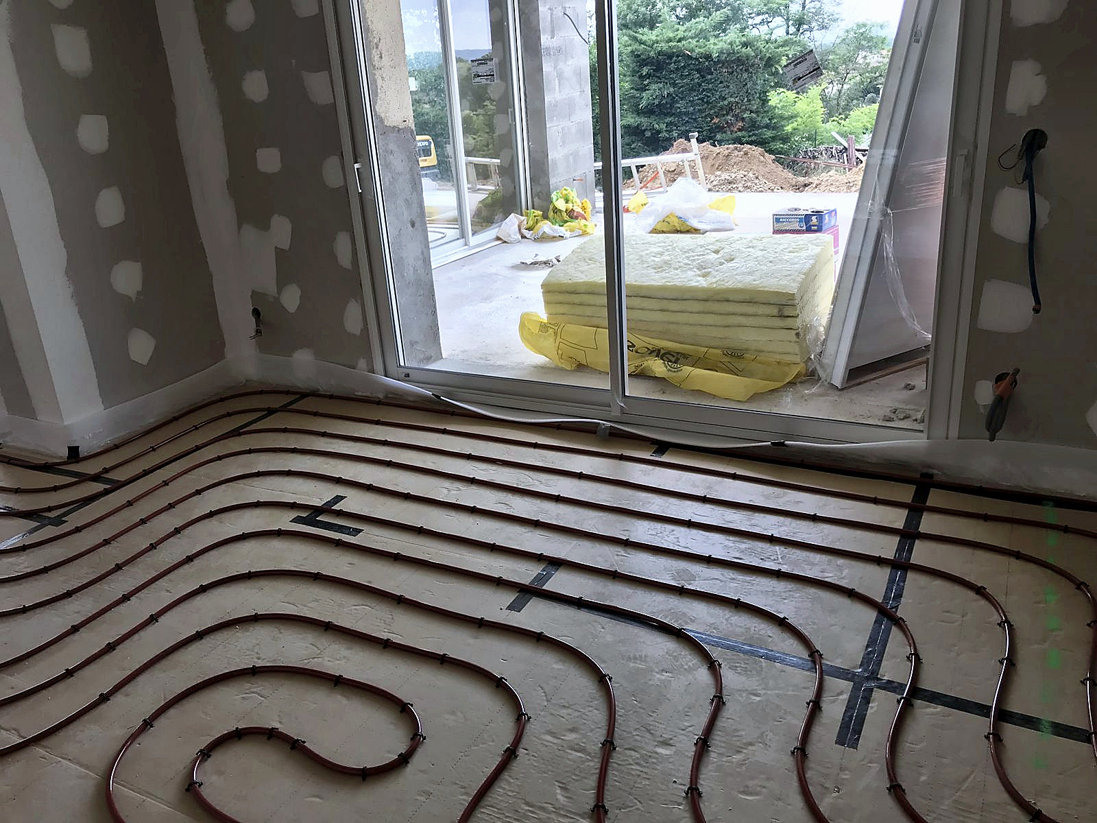 Chantier : plancher chauffant posé devant la nouvelle baie vitrée, à Jonage